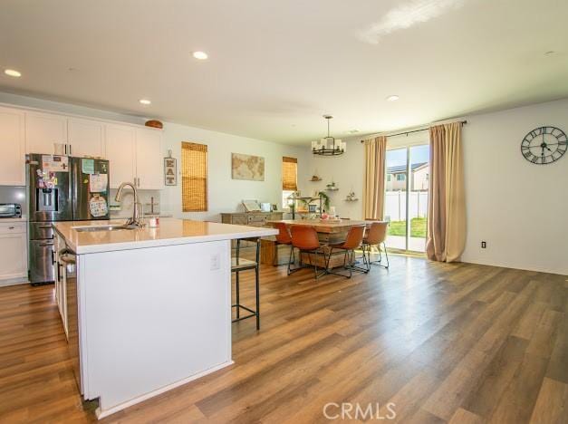 kitchen featuring a sink, wood finished floors, and a center island with sink