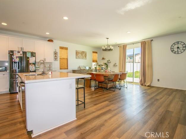 36626 Sevilla Way, Beaumont, CA 92223 - kitchen with fridge with ice dispenser, a center island with sink, wood finished floors, a chandelier, and white cabinetry