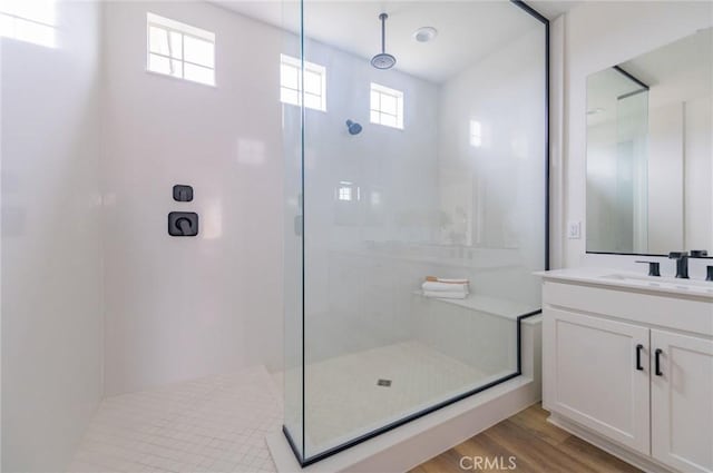 bathroom featuring a shower with shower door, wood finished floors, and vanity