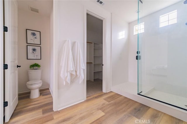 full bath featuring toilet, wood finished floors, visible vents, and walk in shower