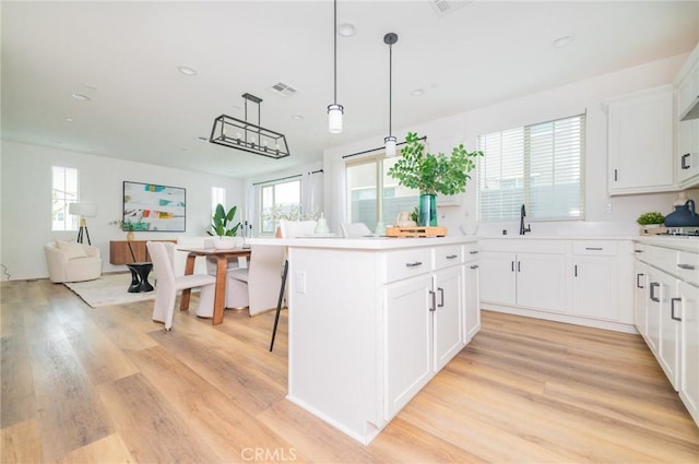 kitchen with visible vents, light wood-type flooring, light countertops, and open floor plan