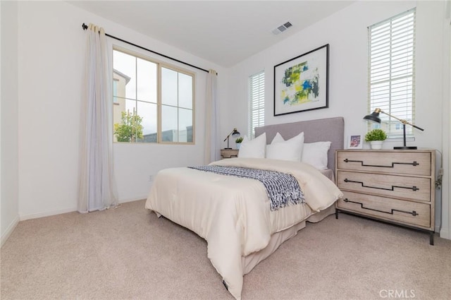 bedroom with visible vents, light carpet, and baseboards