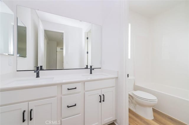 full bathroom featuring a sink, toilet, wood finished floors, and double vanity