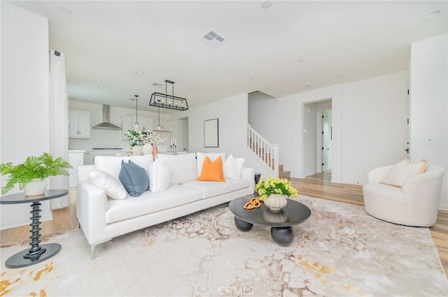 living area featuring visible vents, light wood-style flooring, and stairs