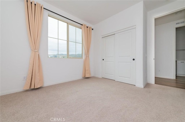 unfurnished bedroom with carpet, visible vents, a closet, and baseboards