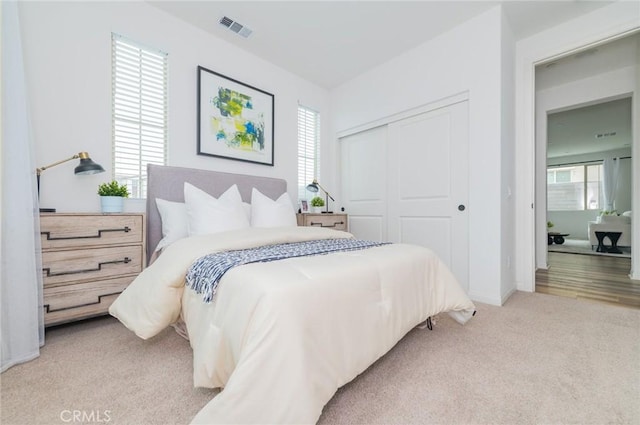 carpeted bedroom with a closet, visible vents, and baseboards