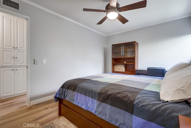 bedroom with visible vents, light wood-style flooring, a ceiling fan, crown molding, and baseboards