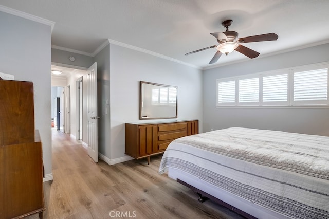 bedroom with crown molding, a ceiling fan, baseboards, and light wood finished floors