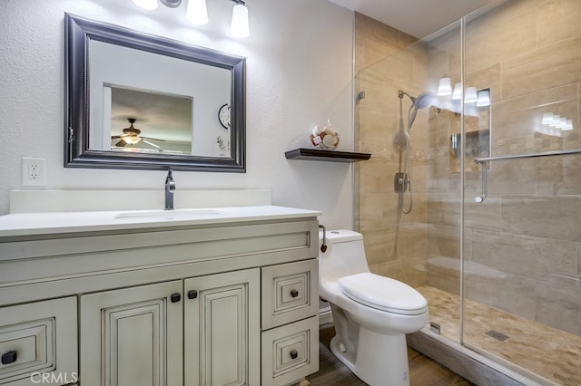 full bath with vanity, wood finished floors, a ceiling fan, a stall shower, and toilet