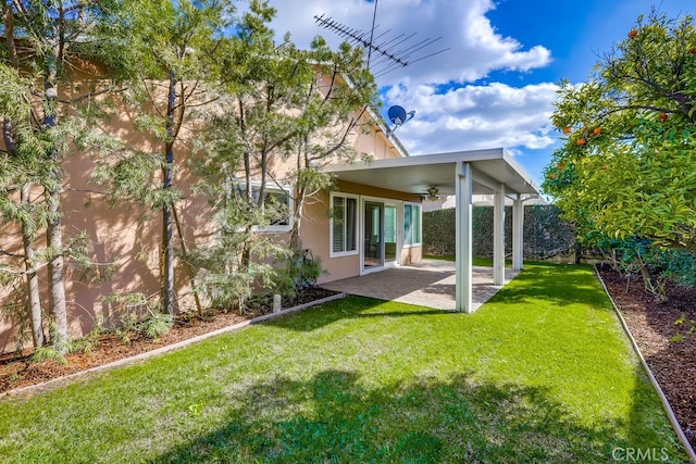 rear view of house featuring a patio area, a lawn, ceiling fan, and stucco siding