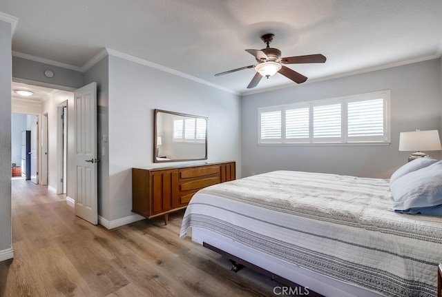 bedroom featuring a ceiling fan, baseboards, light wood finished floors, and ornamental molding