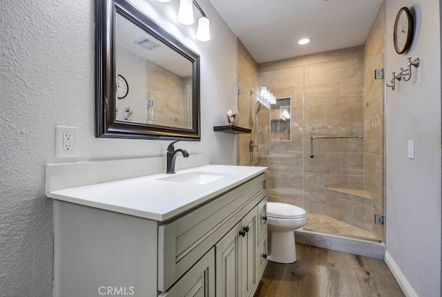 bathroom featuring vanity, wood finished floors, visible vents, a stall shower, and toilet