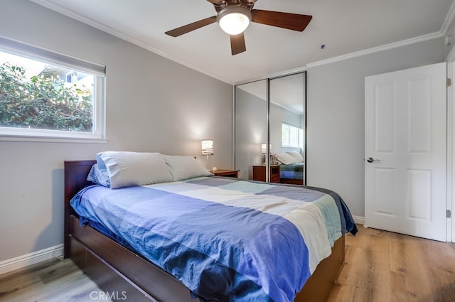 bedroom featuring light wood finished floors, baseboards, crown molding, and a closet