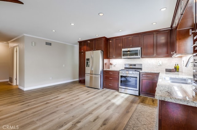 kitchen featuring light wood-type flooring, visible vents, light stone counters, backsplash, and stainless steel appliances