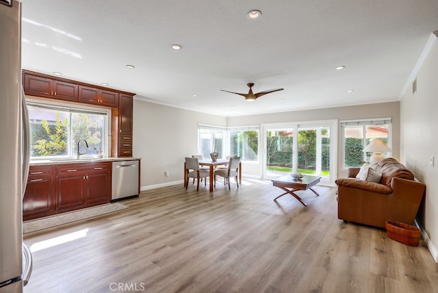 living area with a wealth of natural light, baseboards, light wood-style flooring, and crown molding