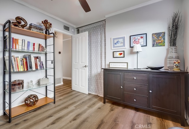 interior space with a ceiling fan, crown molding, wood finished floors, and visible vents