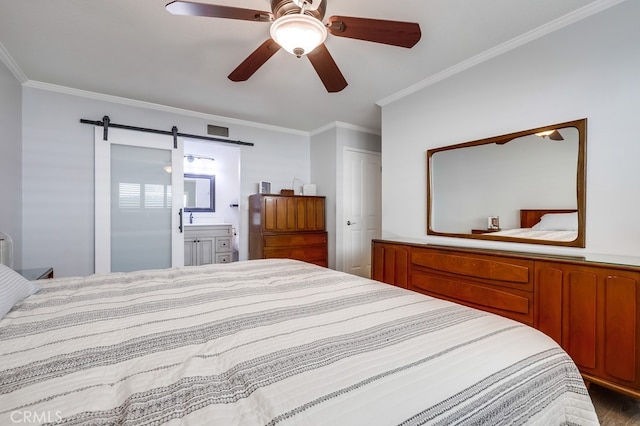 bedroom featuring ceiling fan, a barn door, ornamental molding, and ensuite bathroom