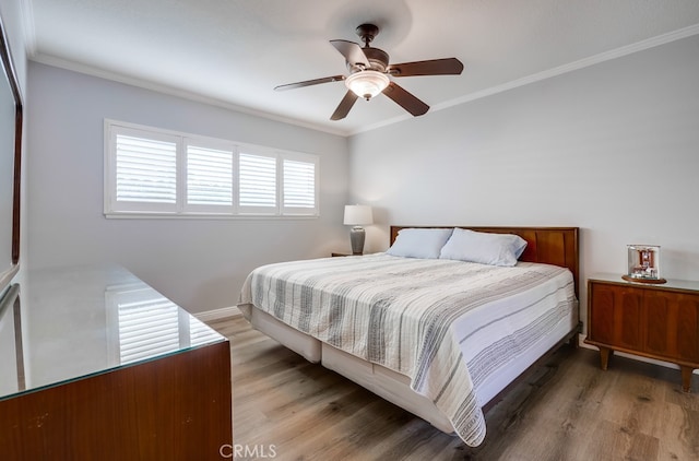 bedroom with light wood-style flooring, crown molding, and a ceiling fan