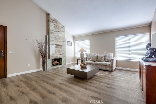 living room featuring high vaulted ceiling, baseboards, light wood-style floors, and a fireplace