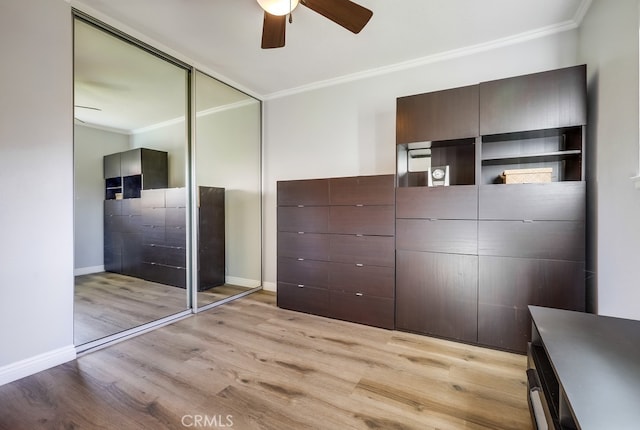 unfurnished bedroom with a closet, crown molding, light wood finished floors, baseboards, and ceiling fan