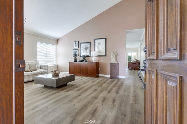 living room featuring baseboards, light wood-style floors, and high vaulted ceiling