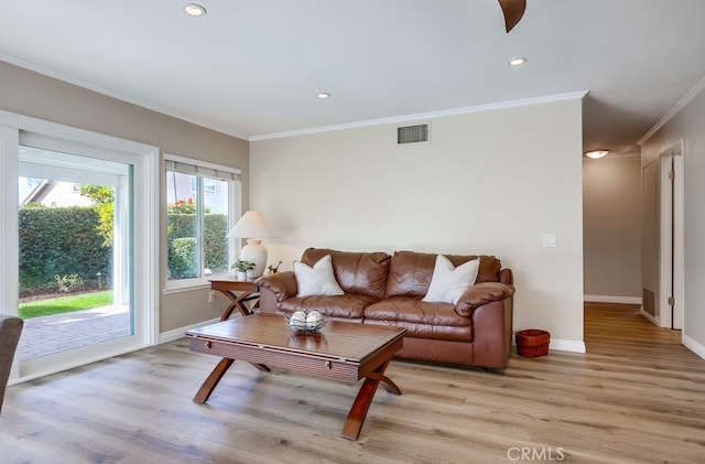 living area with visible vents, light wood-style flooring, baseboards, and ornamental molding