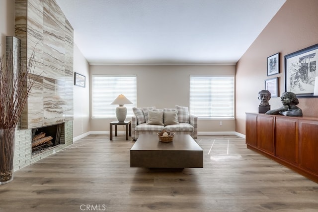 living area with a high end fireplace, plenty of natural light, light wood-type flooring, and baseboards