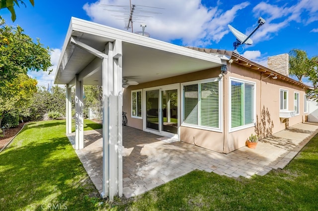 back of property featuring a yard, a patio area, a ceiling fan, and stucco siding