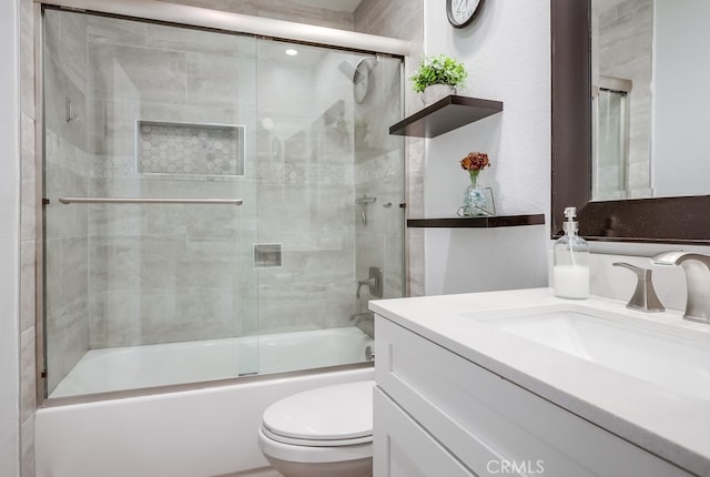 bathroom with vanity, toilet, and combined bath / shower with glass door