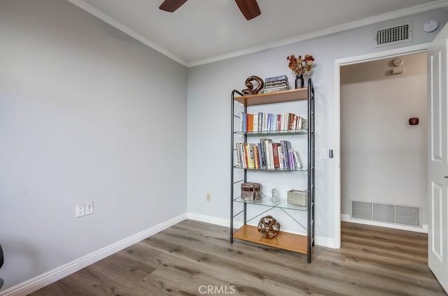 spare room featuring visible vents, ornamental molding, a ceiling fan, and wood finished floors