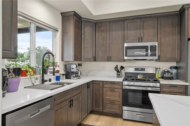 10983 Redwood Ave, Hesperia, CA 92345 - kitchen with appliances with stainless steel finishes, a sink, dark brown cabinetry, and light wood finished floors