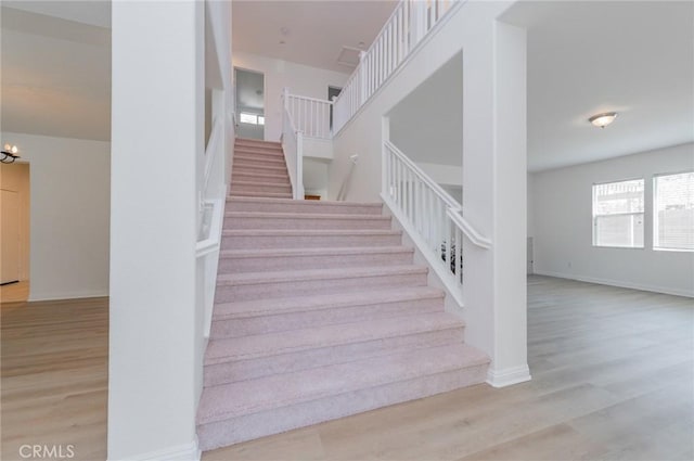 stairs featuring baseboards, a notable chandelier, and wood finished floors