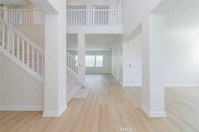 foyer entrance with a towering ceiling, baseboards, wood finished floors, and stairs