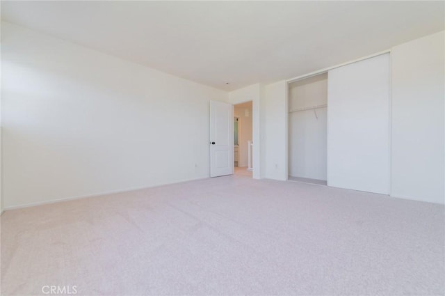 unfurnished bedroom with a closet and light colored carpet