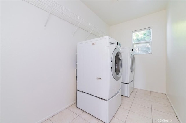 laundry room featuring laundry area, light tile patterned flooring, washing machine and dryer, and baseboards