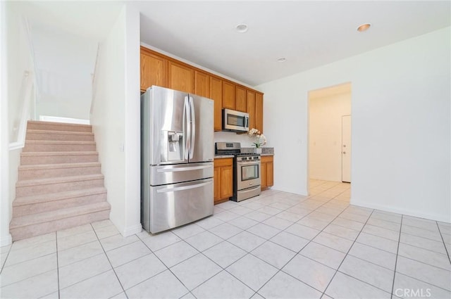 kitchen featuring light tile patterned floors, stainless steel appliances, brown cabinets, and light countertops