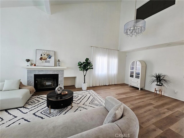 living area featuring a fireplace, a high ceiling, wood finished floors, and baseboards