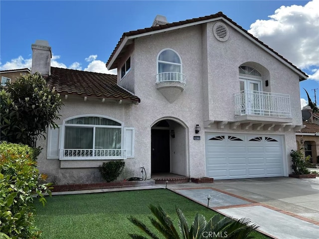 mediterranean / spanish-style house with stucco siding, driveway, a chimney, and a tiled roof