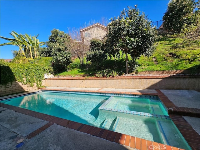 view of swimming pool with a pool with connected hot tub and fence