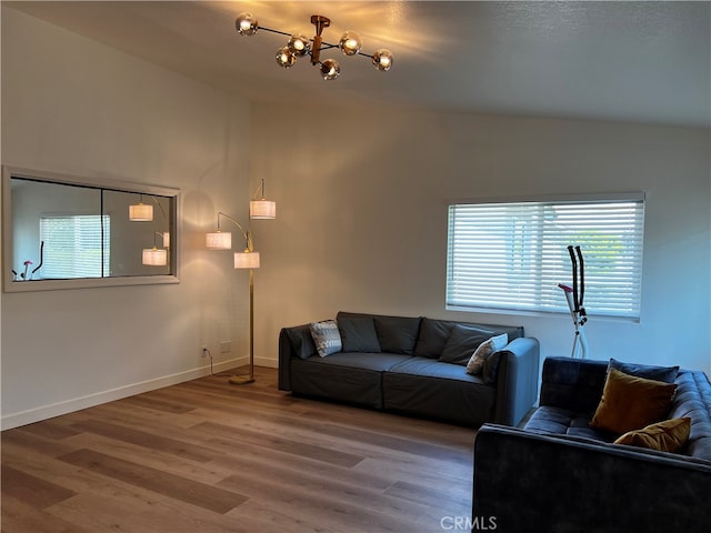 living room with vaulted ceiling, wood finished floors, baseboards, and a chandelier