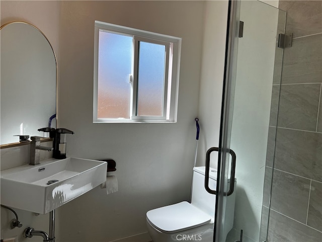 bathroom featuring toilet, a stall shower, and a sink