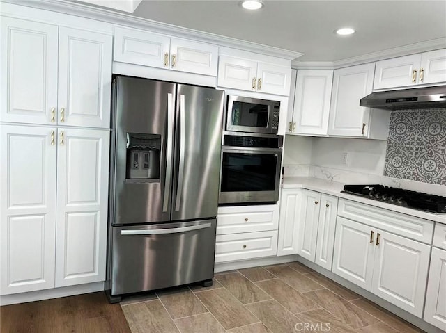 kitchen with recessed lighting, stainless steel appliances, light countertops, white cabinets, and under cabinet range hood