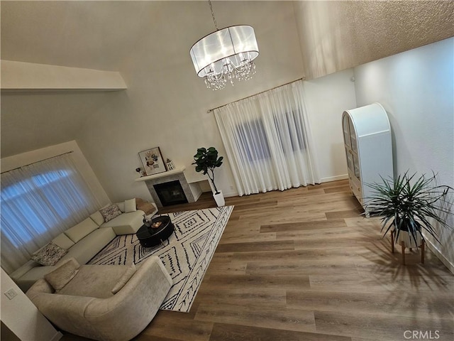 living room featuring a fireplace, a high ceiling, wood finished floors, and a chandelier