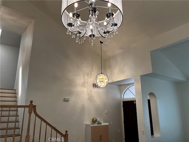 foyer featuring stairs, a notable chandelier, arched walkways, and visible vents