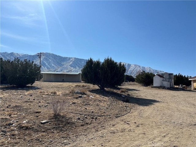 view of yard featuring a mountain view, an outbuilding, and an outdoor structure