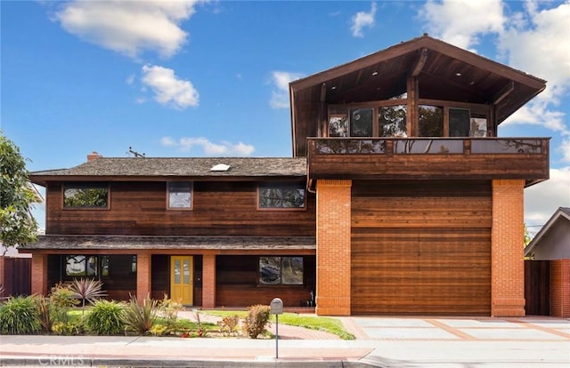 view of front of property featuring a balcony, an attached garage, and driveway