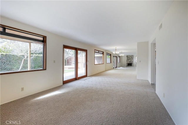 unfurnished room with light carpet, visible vents, and a chandelier