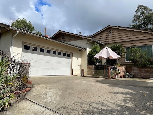 ranch-style home with stucco siding, concrete driveway, and a garage