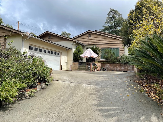 view of front of property with a garage, concrete driveway, and stucco siding