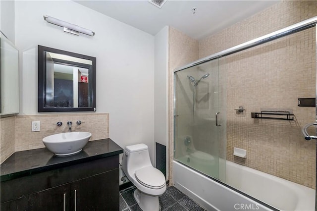 bathroom with tasteful backsplash, toilet, tile patterned floors, vanity, and enclosed tub / shower combo